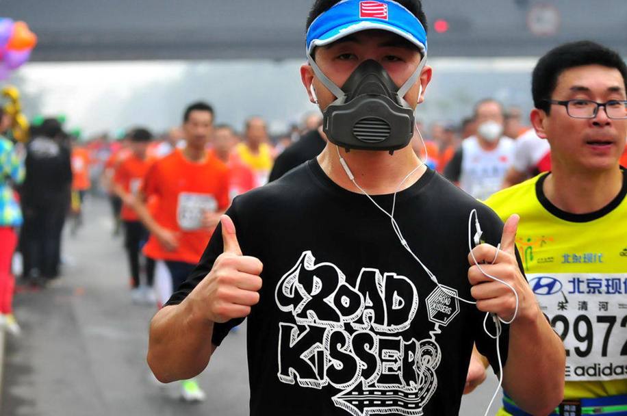 In una Pechino avvolta dallo smog, molti atleti hanno deciso di disputare la 34a edizione della maratona cittadina indossando una mascherina per proteggersi dall’inquinamento (Afp)